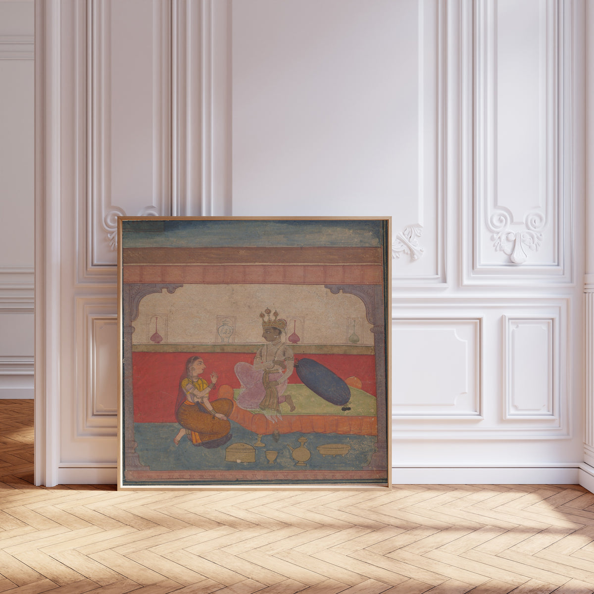Framed art print of Radha Speaks to Krishna by Amber school, leaning against pale pink panelling on a herringbone floor