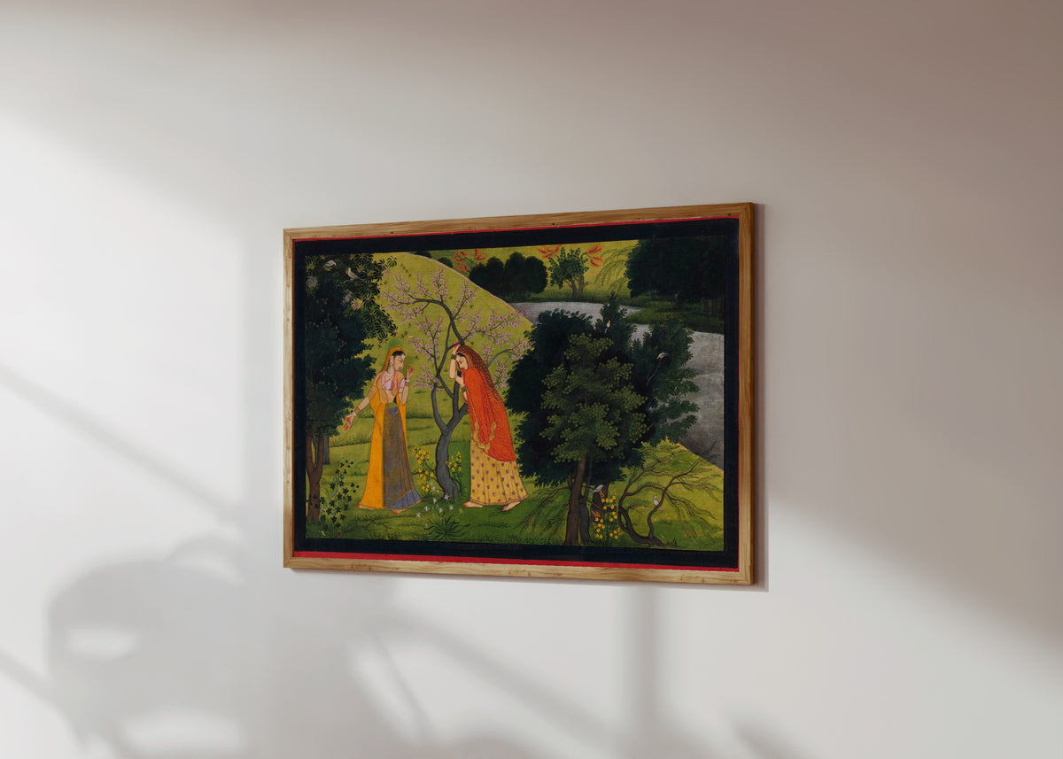Framed art print of Radha with Her Confidant, Pining for Krishna by Garhwal school, in a light wood frame on a sunlit white wall, seen at a slight angle
