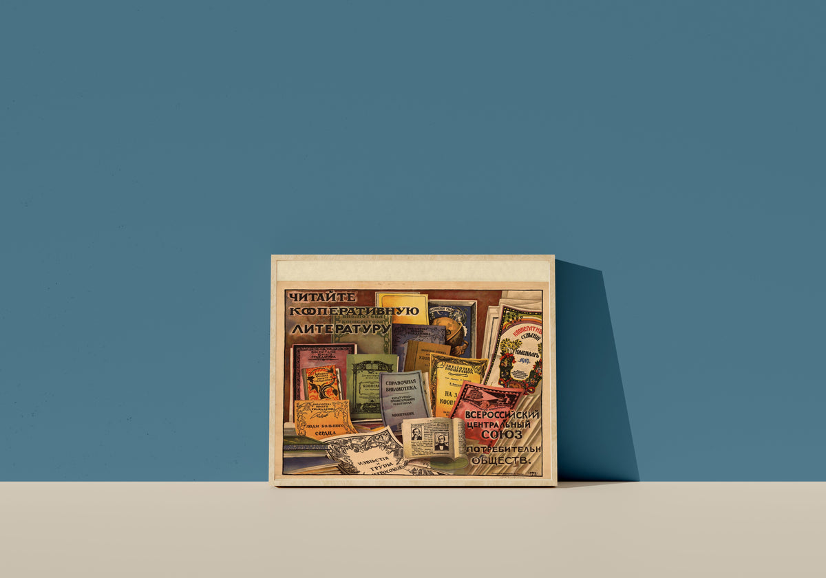 Framed art print of Read Cooperative Literature by Ignaty Nivinsky, in a light wood frame leaning on a blue wall