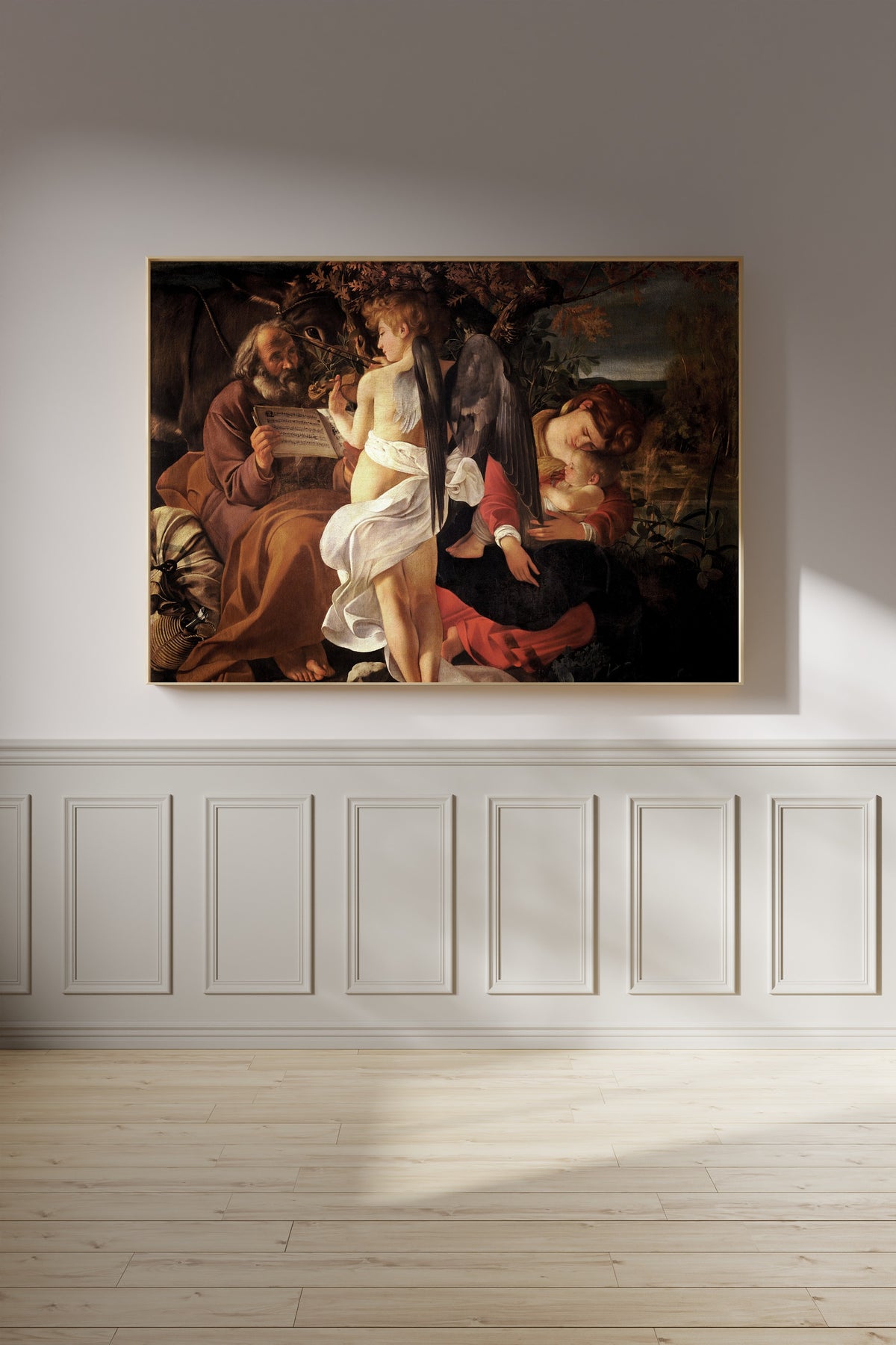 Framed art print of Rest on the Flight into Egypt by Caravaggio, on a panelled wall in afternoon light
