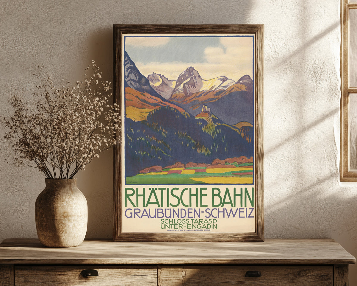 Framed art print of Rhätische Bahn: Graubünden-Schweiz, Schloss… by Emil Cardinaux, in a dark wood frame leaning on a rustic console beside dried flowers