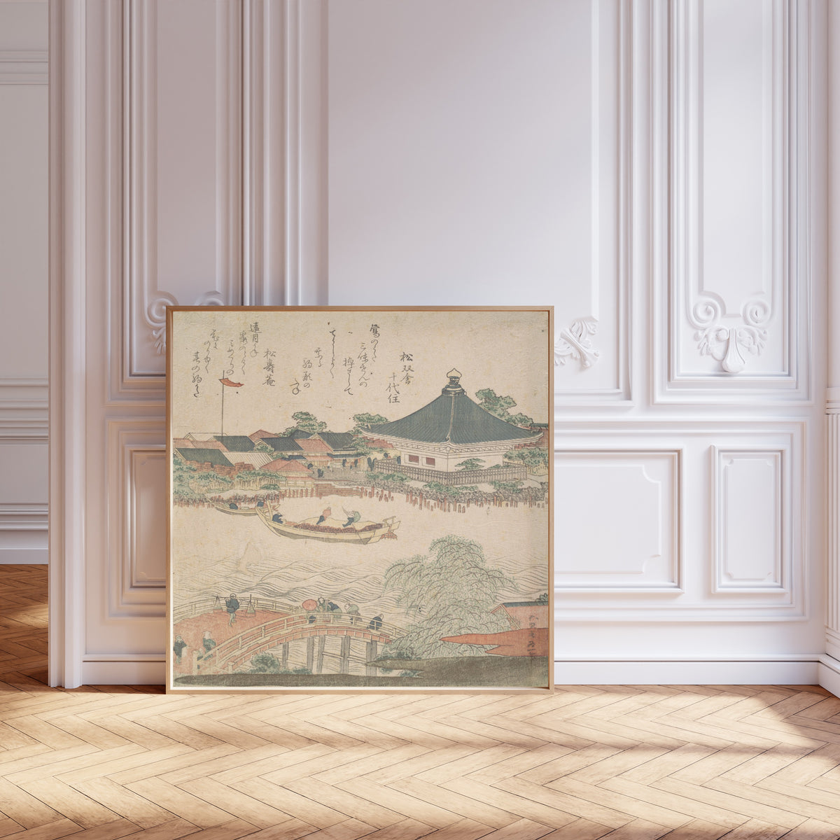 Framed art print of River Scene with Bridge in Foreground by Katsushika Hokusai, leaning against pale pink panelling on a herringbone floor