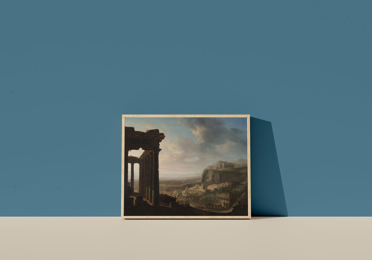 Framed art print of Ruins of an Ancient City by John Martin, in a light wood frame leaning on a blue wall