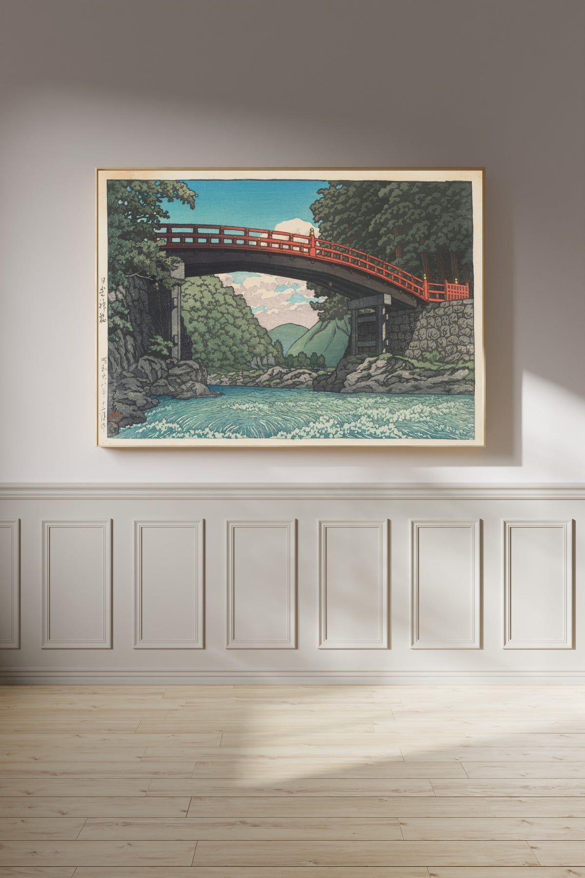 Framed art print of Sacred Bridge, Nikko by Kawase Hasui, on a panelled wall in afternoon light