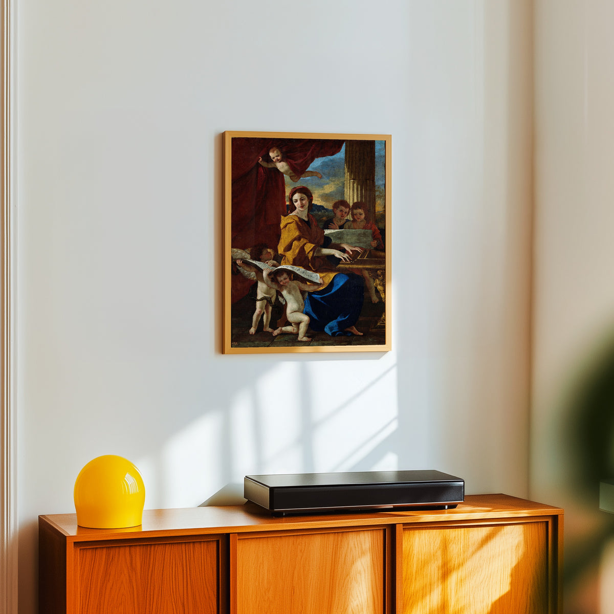 Framed art print of Saint Cecilia by Nicolas Poussin, in a light wood frame on a white wall above an orange sideboard