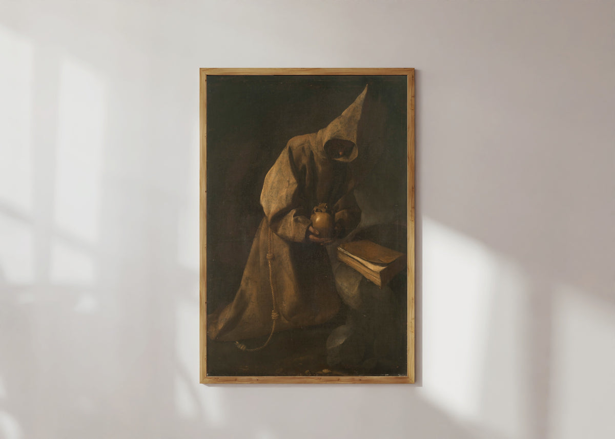 Framed art print of Saint Francis in Meditation by Francisco de Zurbarán, in a light wood frame on a sunlit white wall