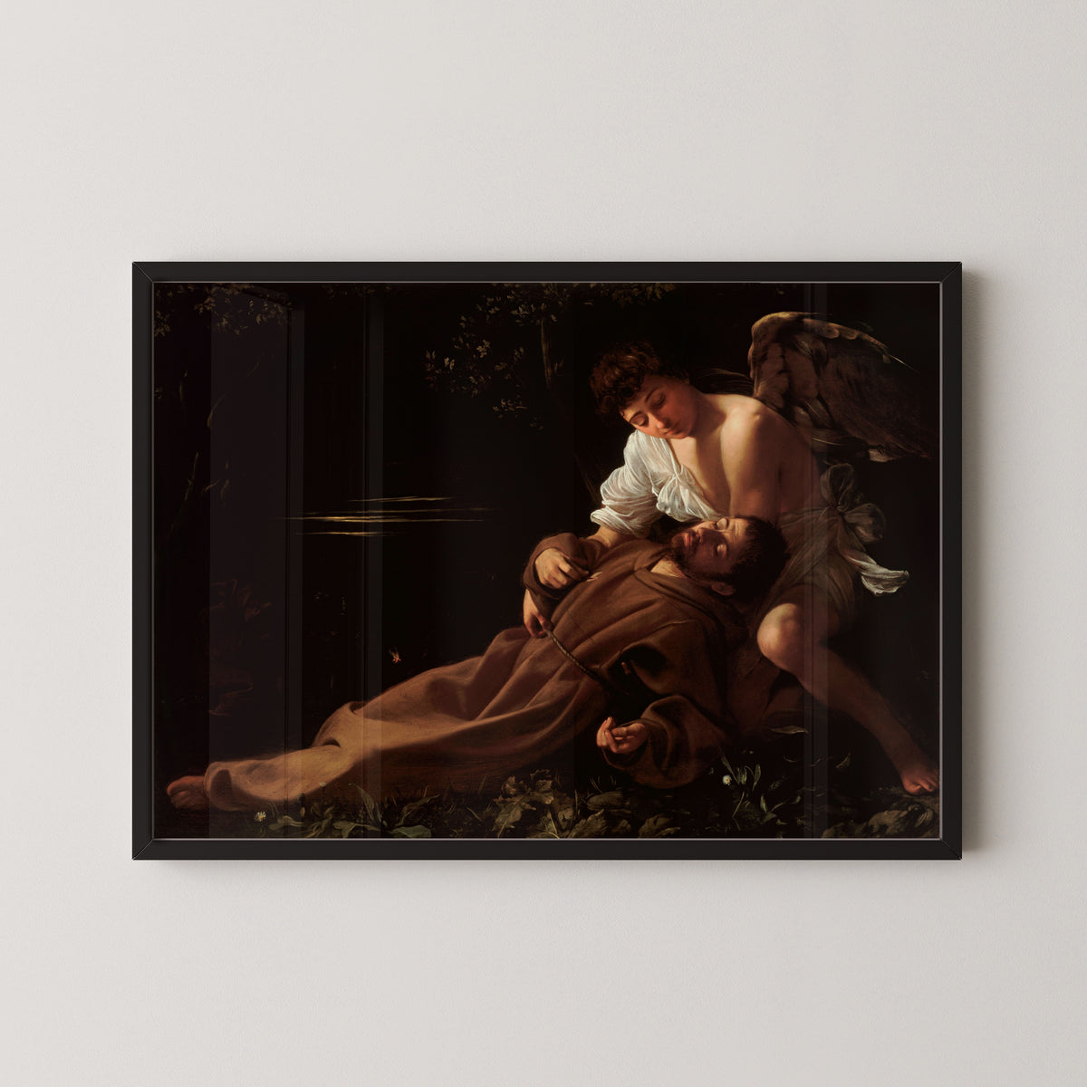 Framed art print of Saint Francis of Assisi in Ecstasy by Caravaggio, in a black frame on a pale wall