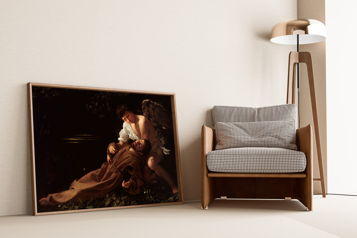 Framed art print of Saint Francis of Assisi in Ecstasy by Caravaggio, leaning against a wall beside an armchair and a floor lamp