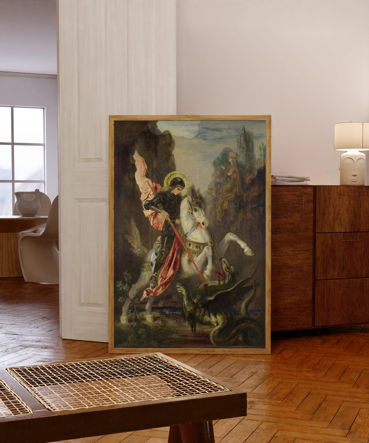 Framed art print of Saint George and the Dragon by Gustave Moreau, in a light wood frame leaning in a warm room with a parquet floor
