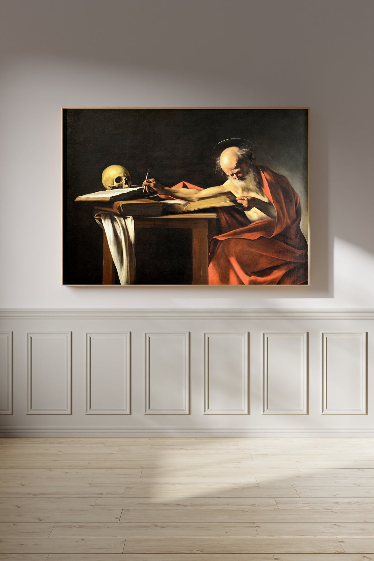 Framed art print of Saint Jerome Writing by Caravaggio, on a panelled wall in afternoon light