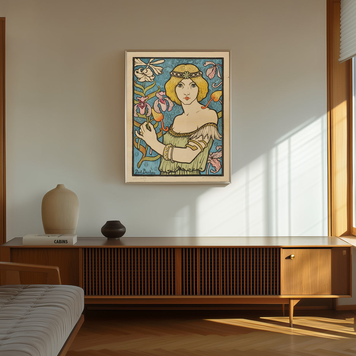 Framed art print of Salon des Cent: 17e Exposition (unlettered state) by Paul Berthon, in a thin light frame on a sunlit wall above a wooden sideboard