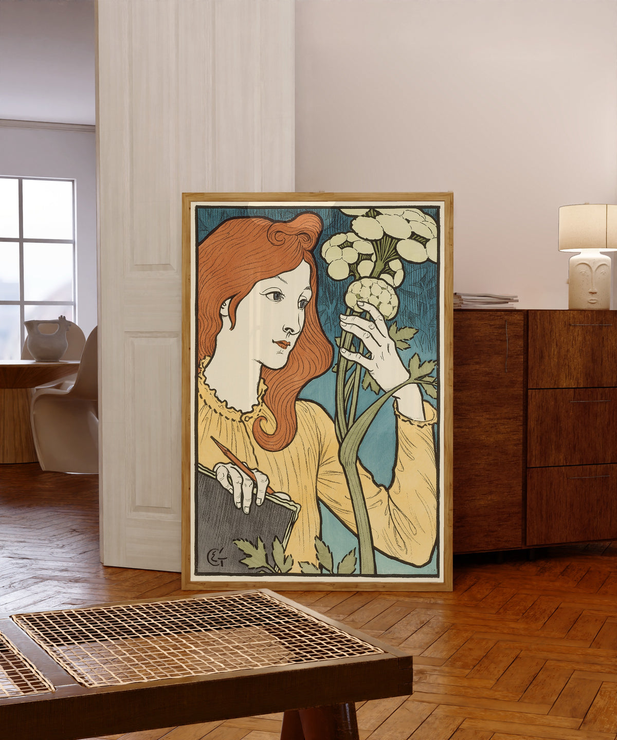 Framed art print of Salon des Cent by Eugène Grasset, in a light wood frame leaning in a warm room with a parquet floor