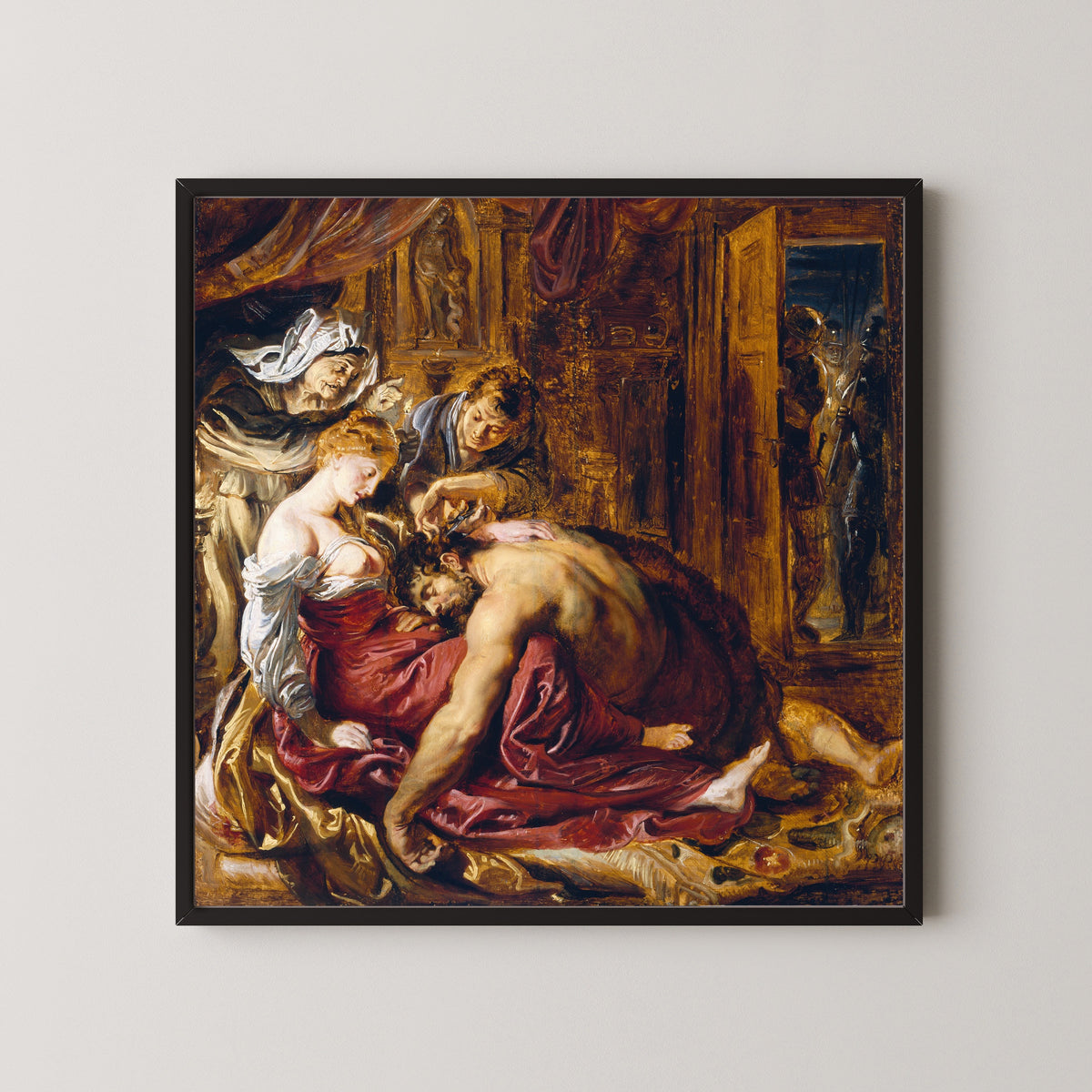 Framed art print of Samson and Delilah by Peter Paul Rubens, in a black frame on a pale wall