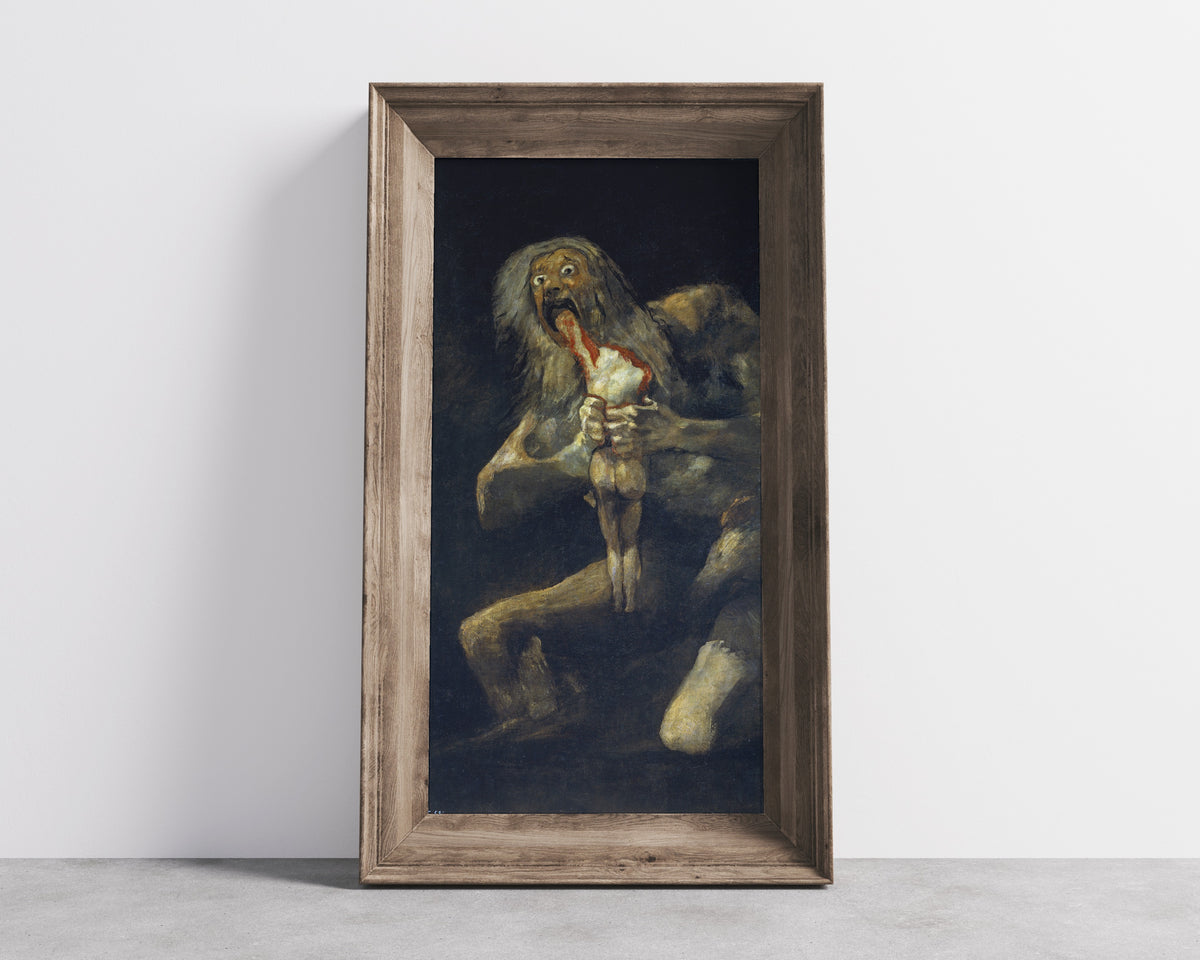 Framed art print of Saturn Devouring His Son by Francisco de Goya, in a wide wooden frame leaning against a concrete wall