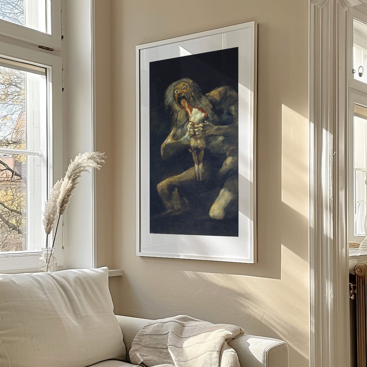 Framed art print of Saturn Devouring His Son by Francisco de Goya, in a sunlit living room above a sofa