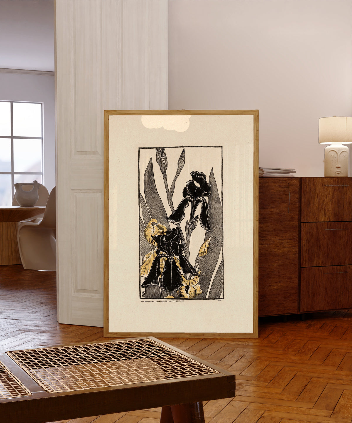 Framed art print of Schwertlilien by Otto Eckmann, in a light wood frame leaning in a warm room with a parquet floor