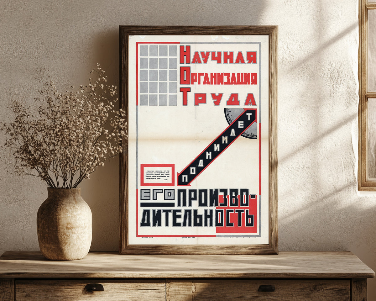 Framed art print of Scientific organisation of labour raises its productivity, in a dark wood frame leaning on a rustic console beside dried flowers