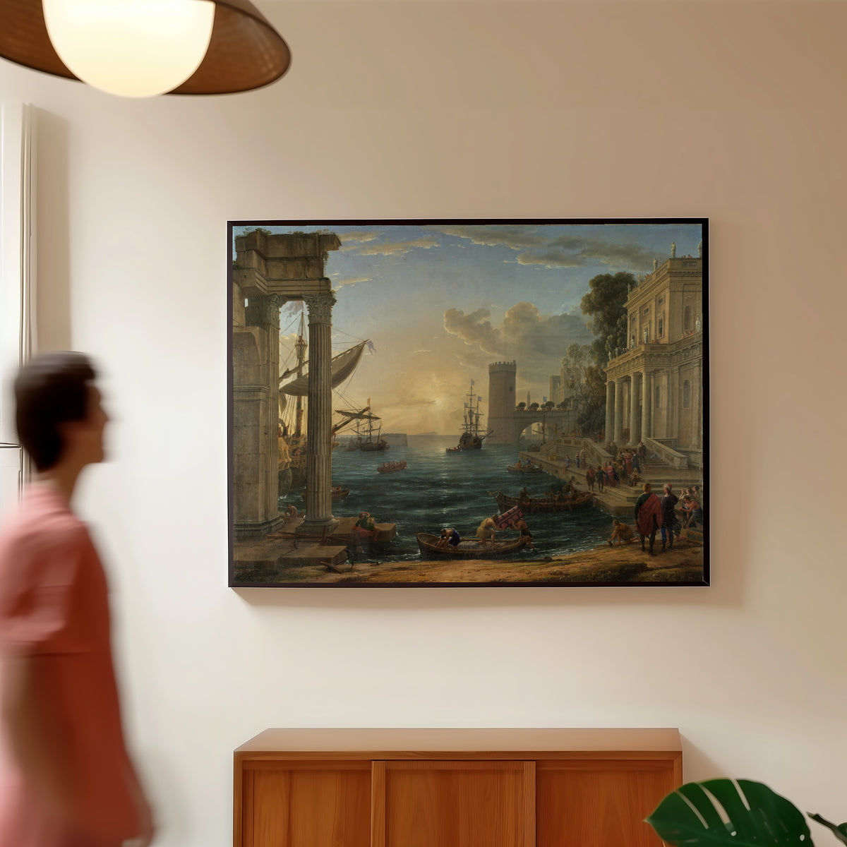 Framed art print of Seaport with the Embarkation of the Queen of Sheba by Claude Lorrain, in a slim black frame on a warm wall in a sunlit room