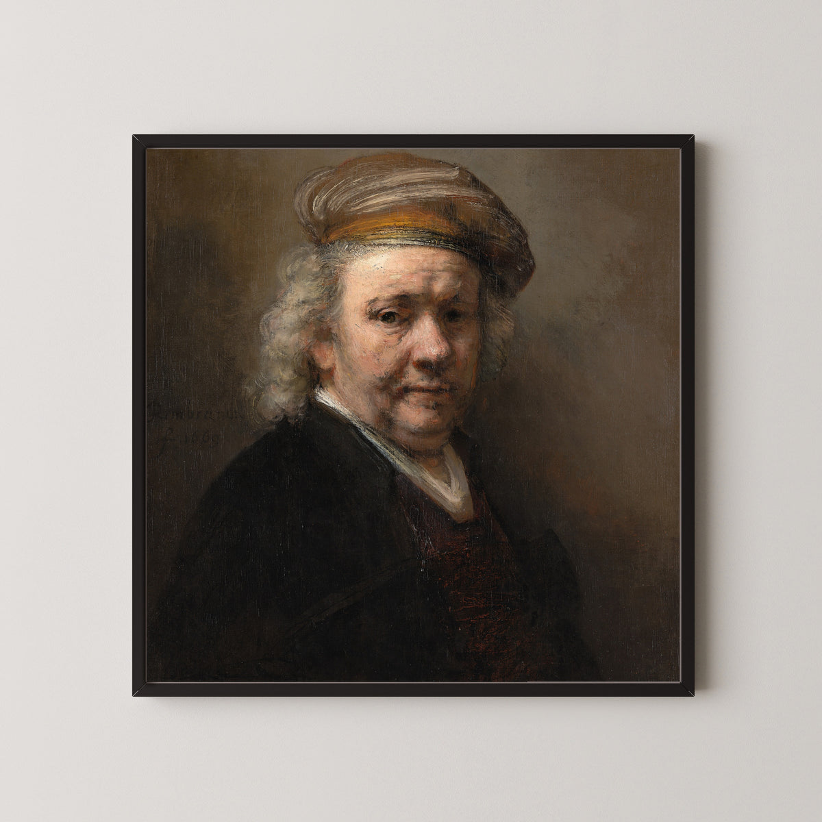 Framed art print of Self-Portrait (1669) by Rembrandt van Rijn, in a black frame on a pale wall