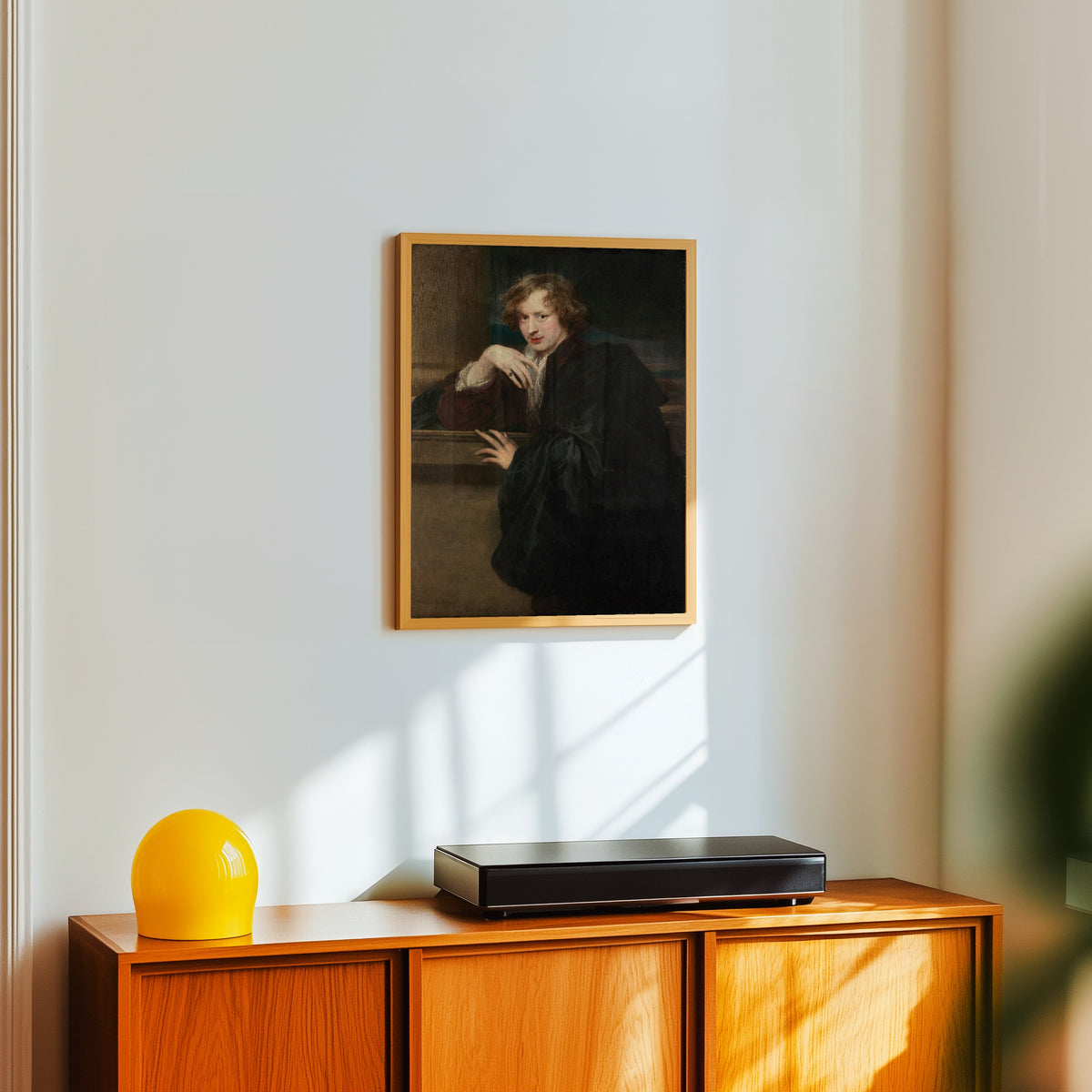 Framed art print of Self-Portrait by Anthony van Dyck, in a light wood frame on a white wall above an orange sideboard