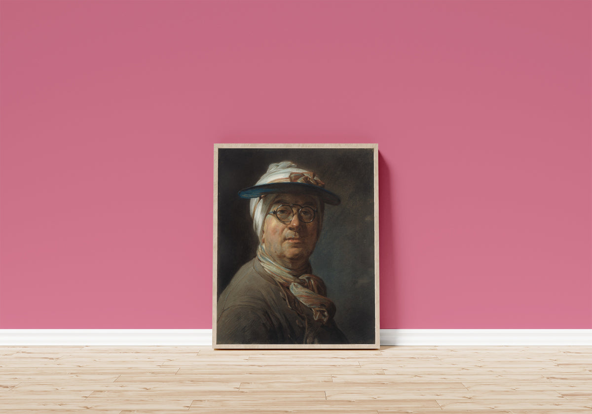 Framed art print of Self-Portrait with a Visor by Jean-Siméon Chardin, in a light wood frame leaning on a pink wall above a wooden floor