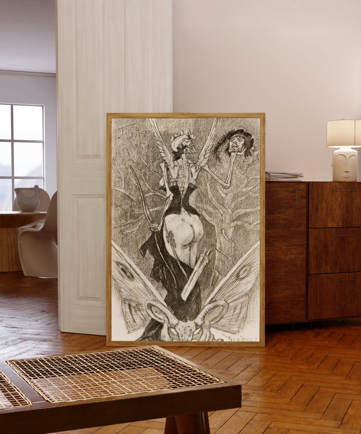 Framed art print of Sentimental Initiation by Félicien Rops, in a light wood frame leaning in a warm room with a parquet floor
