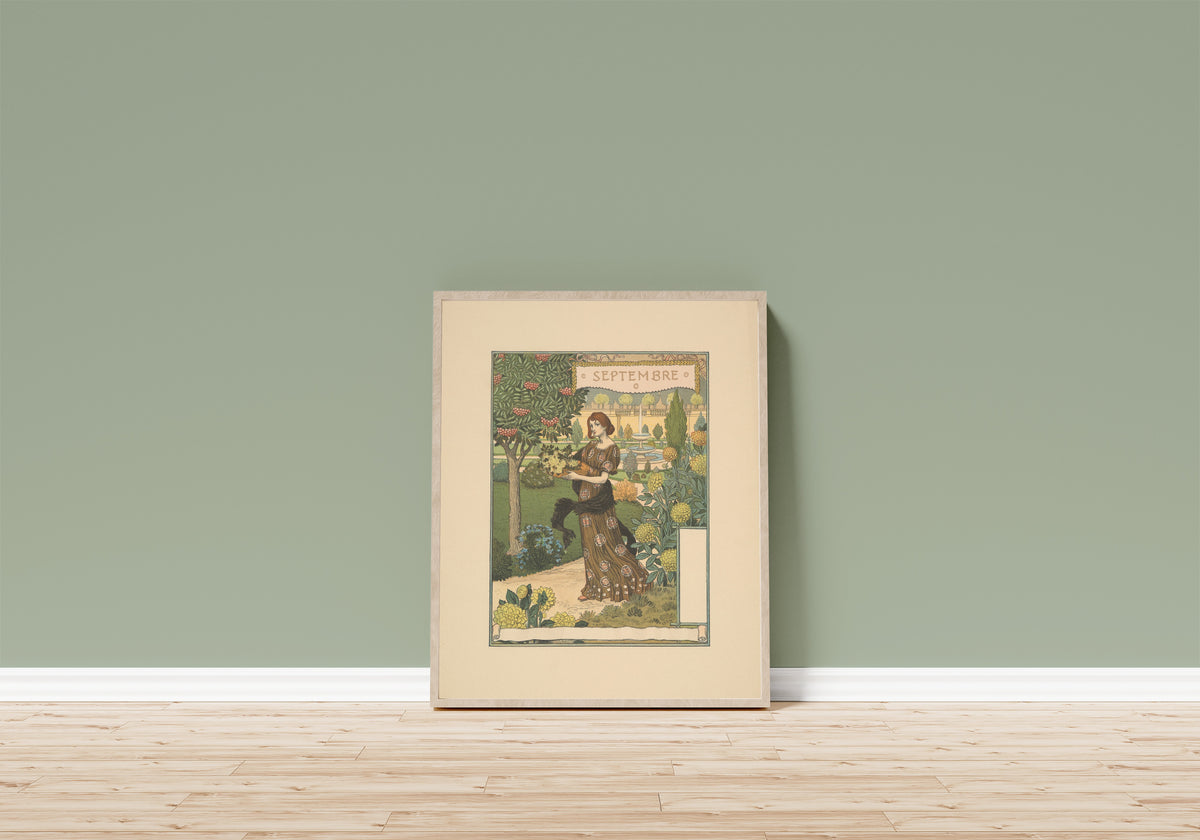 Framed art print of Septembre by Eugène Grasset, in a light wood frame leaning on a sage green wall above a wooden floor