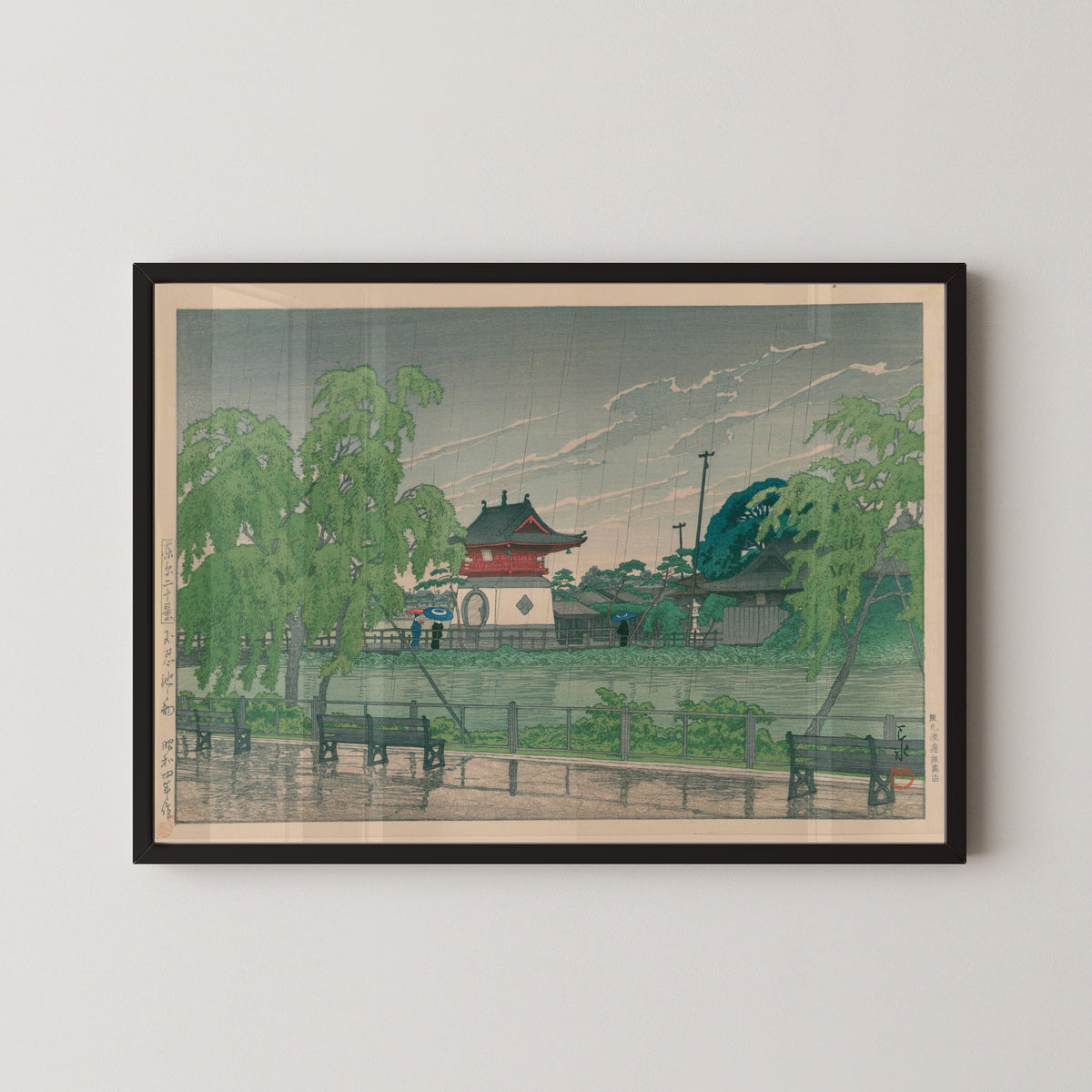 Framed art print of Shinobazu Pond in Rain by Kawase Hasui, in a black frame on a pale wall