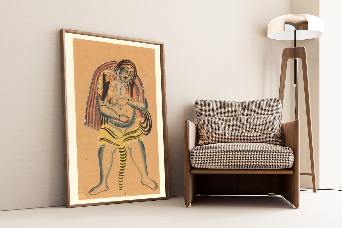 Framed art print of Shiva Carries the Corpse of Sati by Kalighat painter, leaning against a wall beside an armchair and a floor lamp