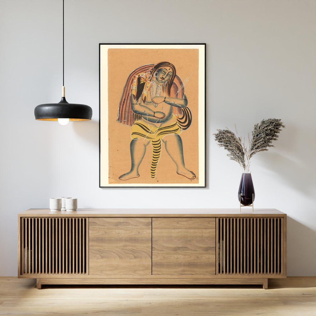 Framed art print of Shiva Carries the Corpse of Sati by Kalighat painter, above a slatted wood sideboard