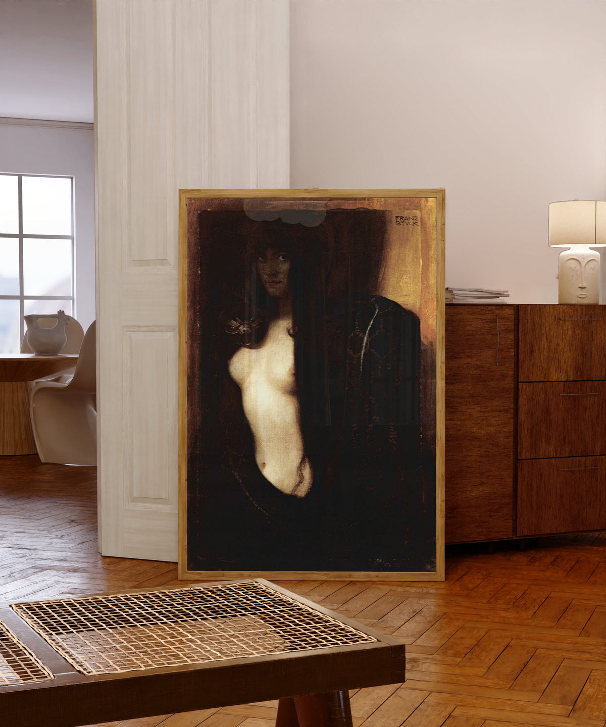 Framed art print of Sin (Die Sünde) by Franz von Stuck, in a light wood frame leaning in a warm room with a parquet floor