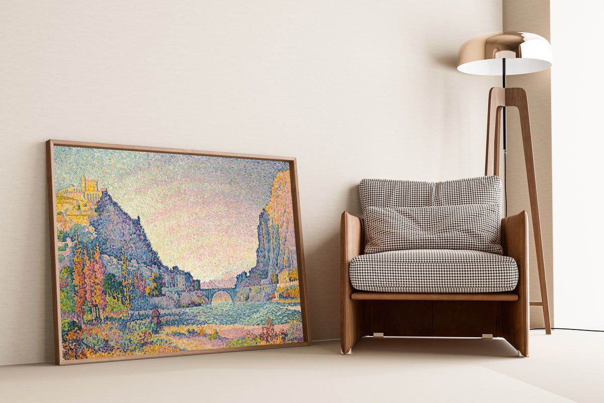 Framed art print of Sisteron by Paul Signac, leaning against a wall beside an armchair and a floor lamp