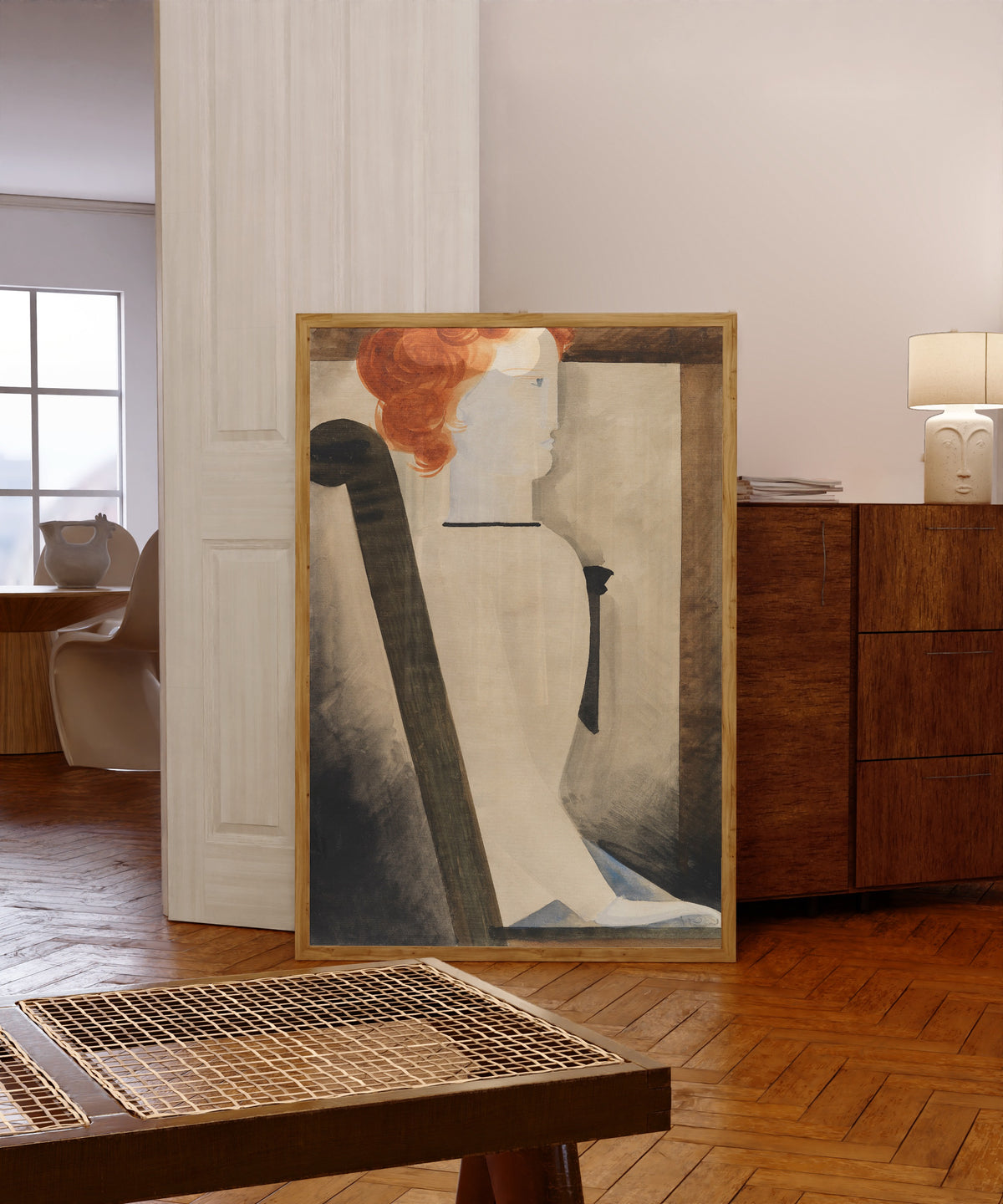 Framed art print of Sitzende by Oskar Schlemmer, in a light wood frame leaning in a warm room with a parquet floor