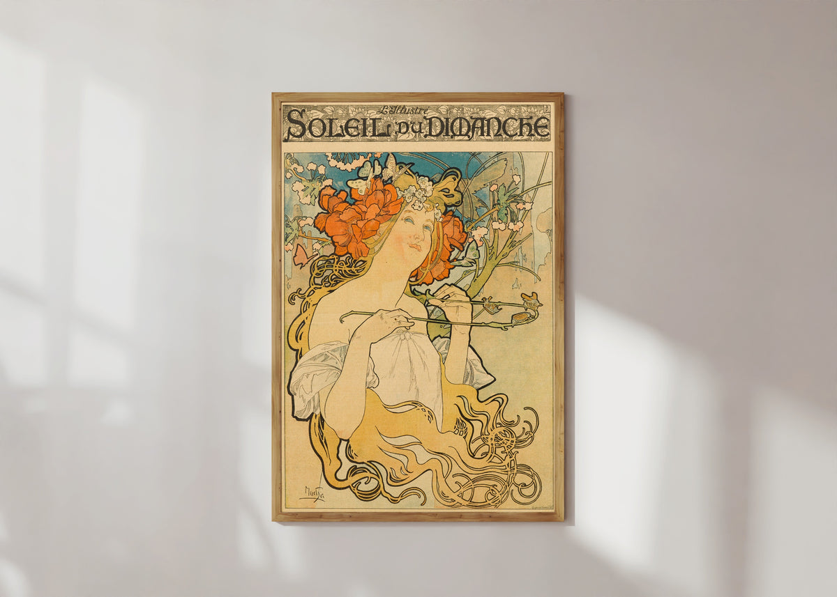 Framed art print of Soleil du Dimanche by Alphonse Mucha, in a light wood frame on a sunlit white wall