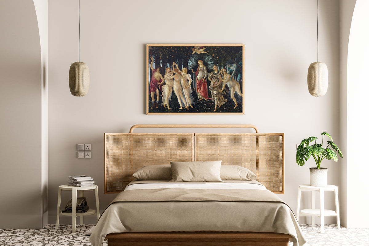 Framed art print of Spring by Sandro Botticelli, above a cane-headboard bed