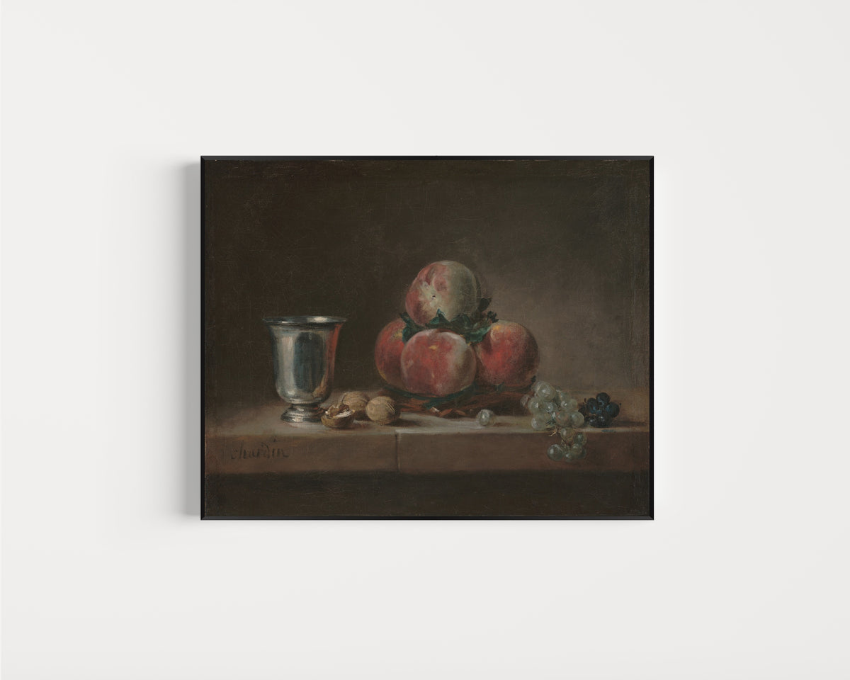 Framed art print of Still Life with Peaches, a Silver Goblet, Grapes, and Walnuts by Jean-Siméon Chardin, in a slim black frame on a plain white wall