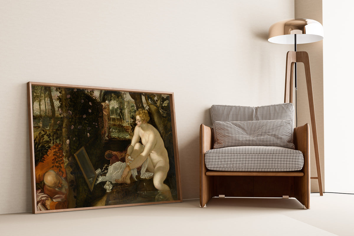 Framed art print of Susanna and the Elders by Tintoretto, leaning against a wall beside an armchair and a floor lamp