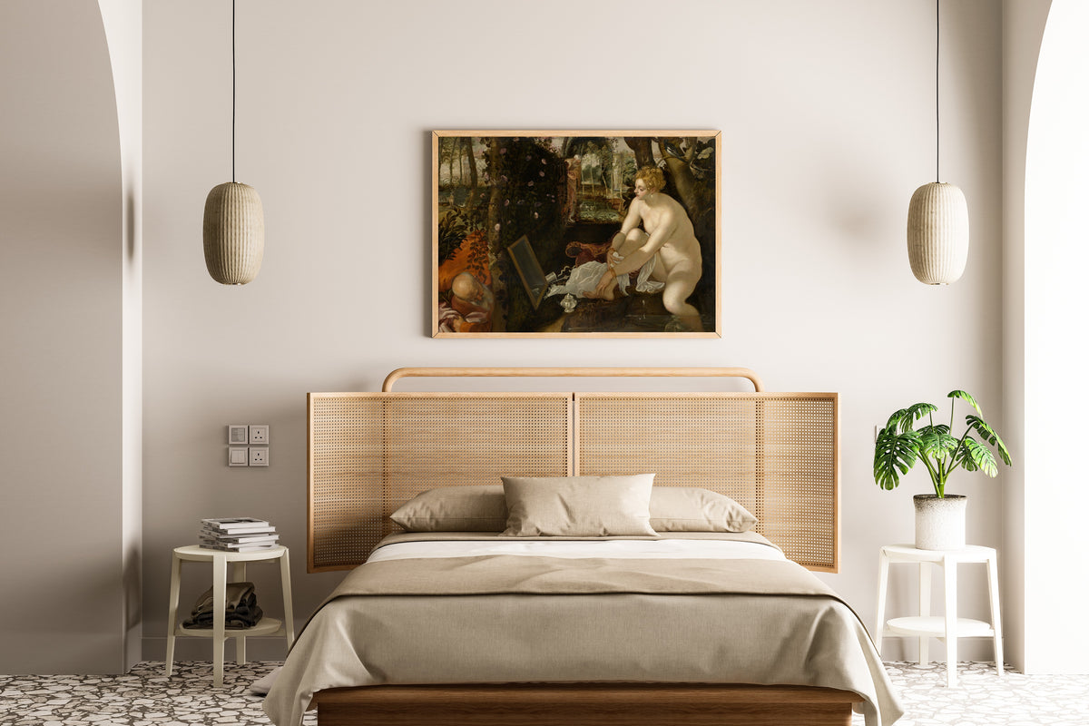 Framed art print of Susanna and the Elders by Tintoretto, above a cane-headboard bed