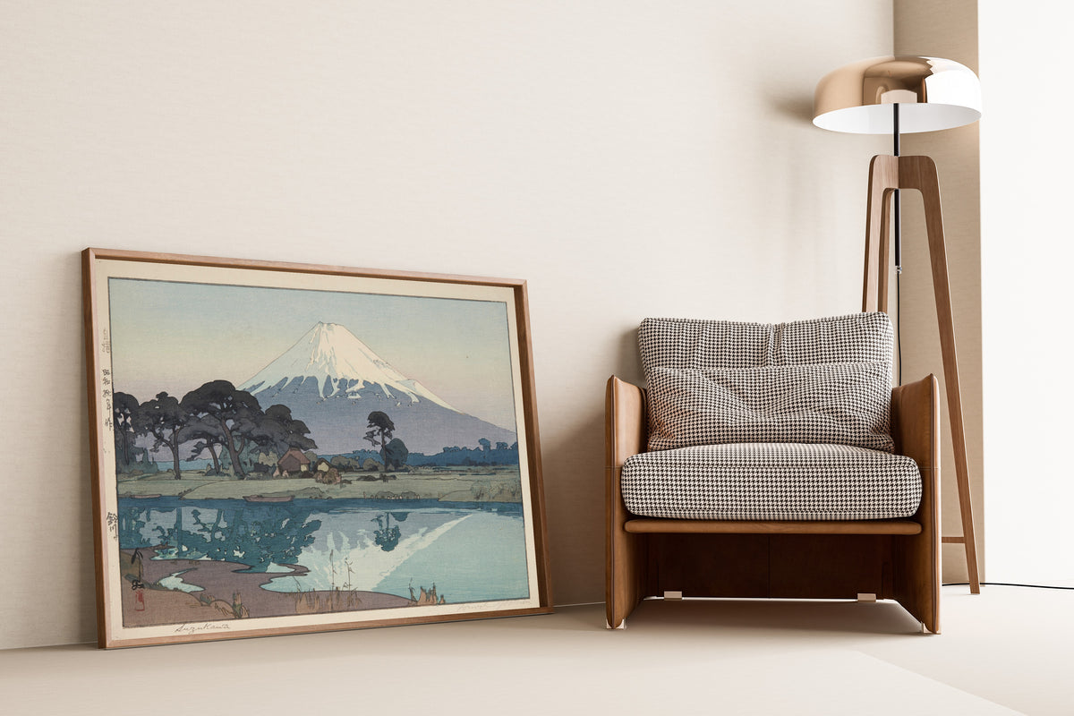 Framed art print of Suzukawa by Hiroshi Yoshida, leaning against a wall beside an armchair and a floor lamp