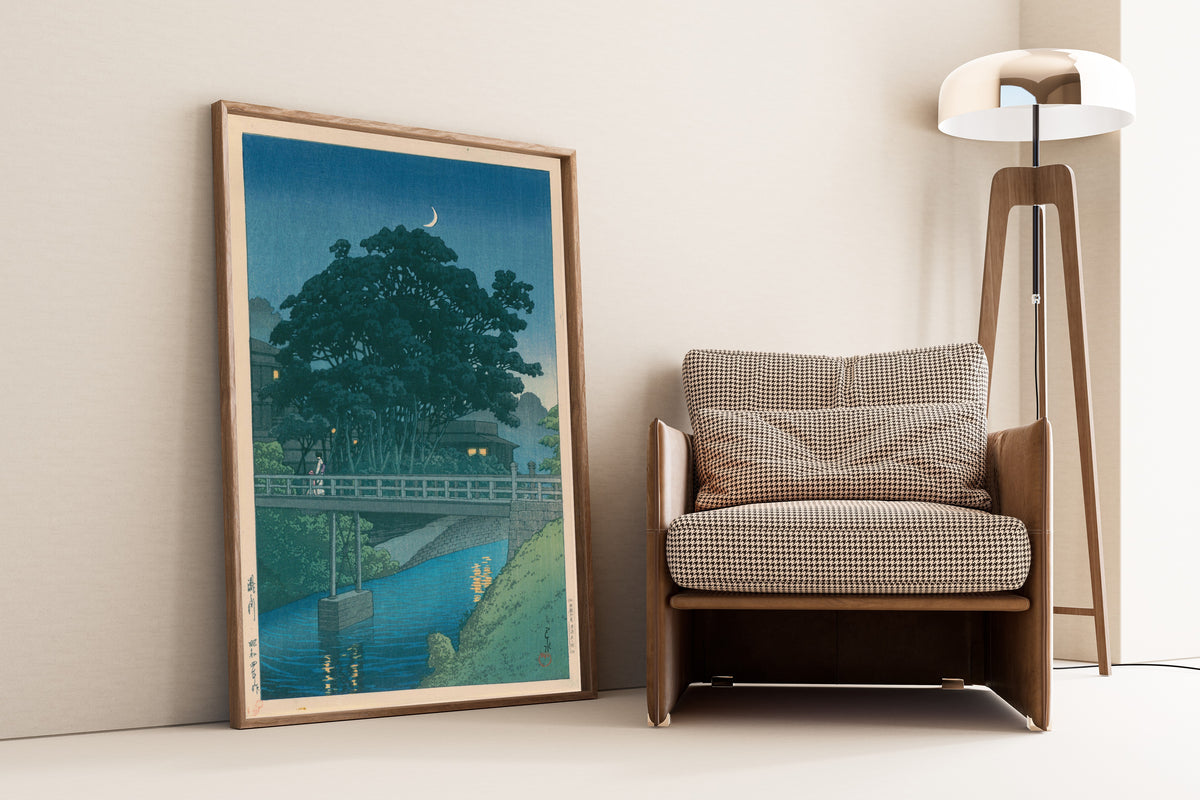 Framed art print of Takinogawa River by Kawase Hasui, leaning against a wall beside an armchair and a floor lamp