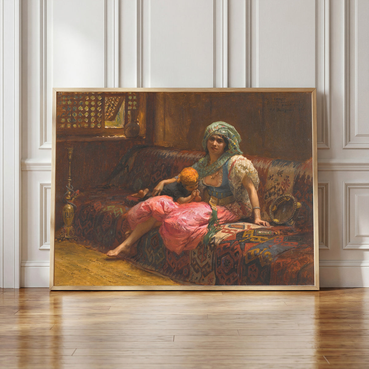 Framed art print of Tender Moments by Frederick Arthur Bridgman, in a light wood frame leaning against a panelled white wall