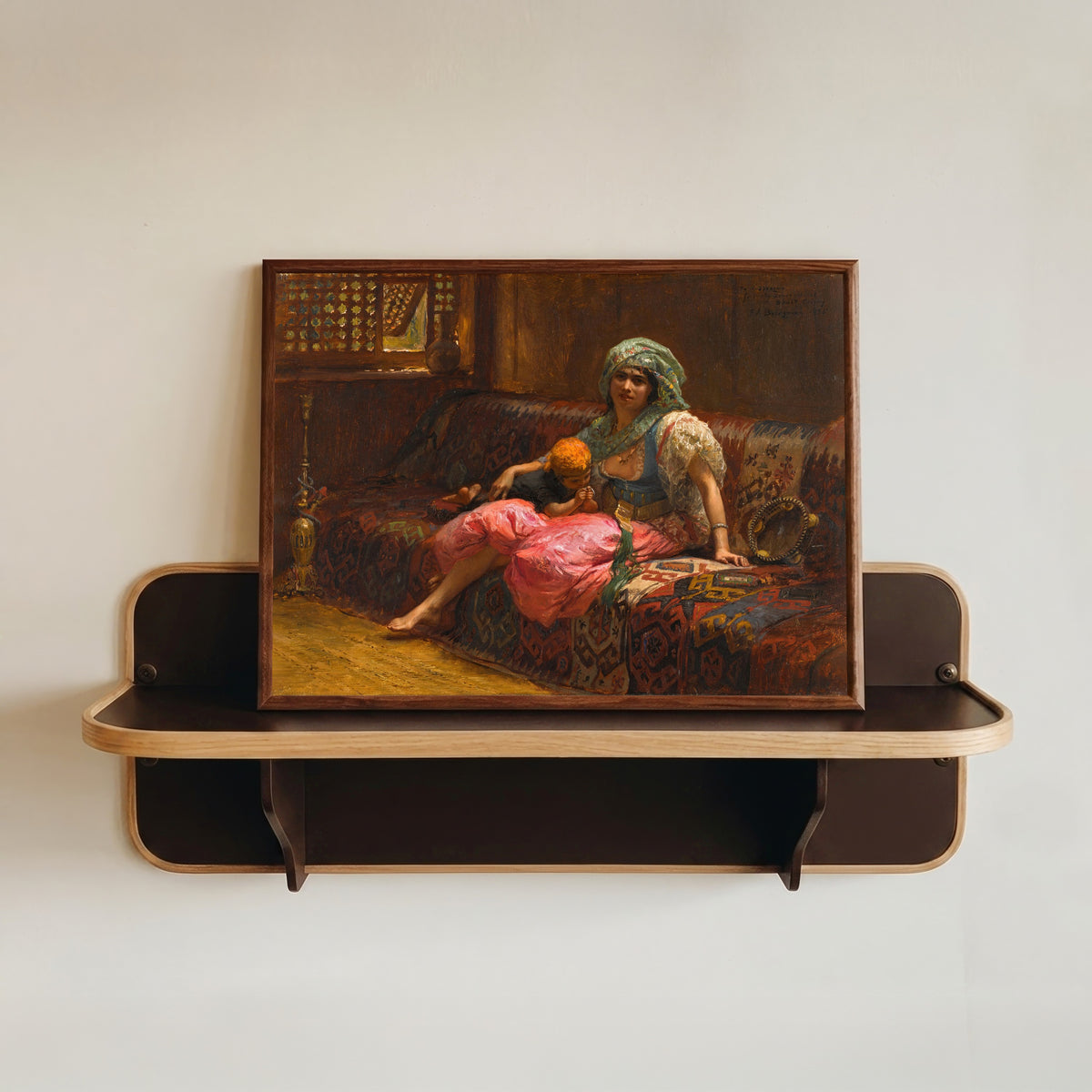 Framed art print of Tender Moments by Frederick Arthur Bridgman, in a dark wood frame resting on a wall shelf
