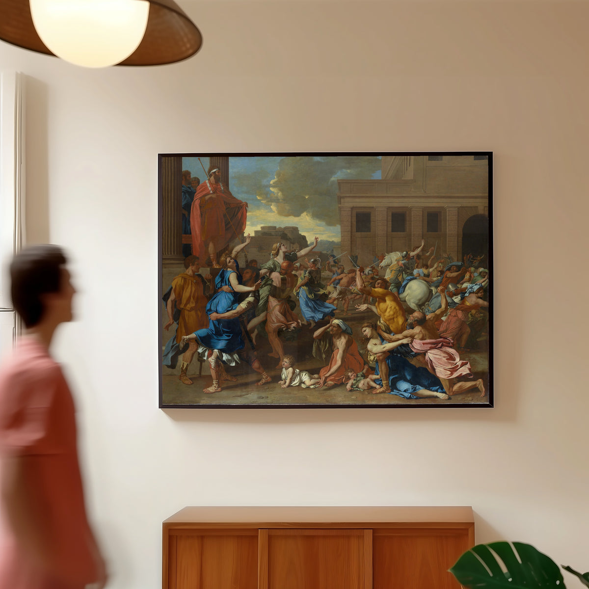 Framed art print of The Abduction of the Sabine Women by Nicolas Poussin, in a slim black frame on a warm wall in a sunlit room
