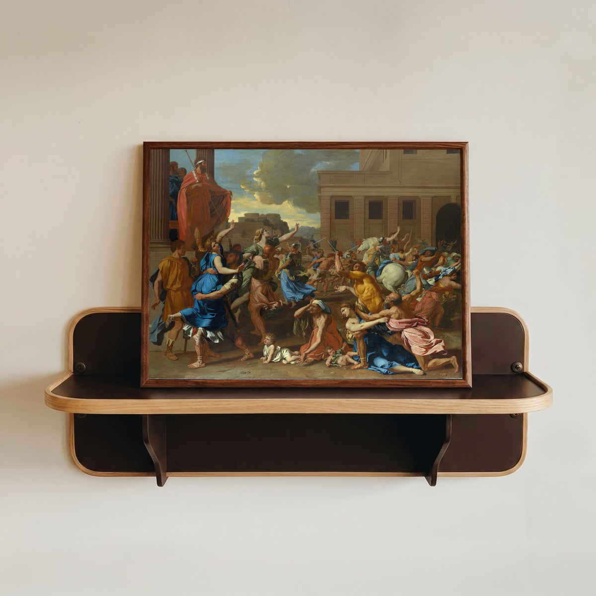 Framed art print of The Abduction of the Sabine Women by Nicolas Poussin, in a dark wood frame resting on a wall shelf