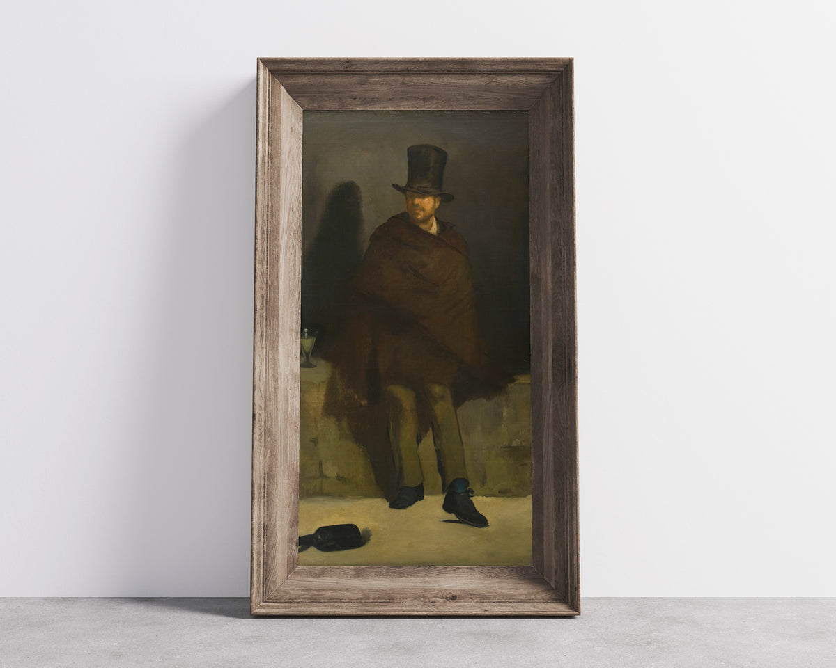 Framed art print of The Absinthe Drinker by Édouard Manet, in a wide wooden frame leaning against a concrete wall