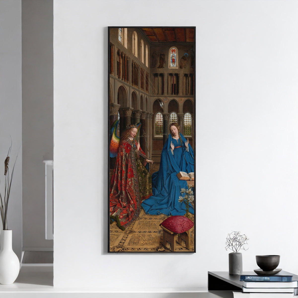 Framed art print of The Annunciation by Jan van Eyck, on a white wall above books and a bowl