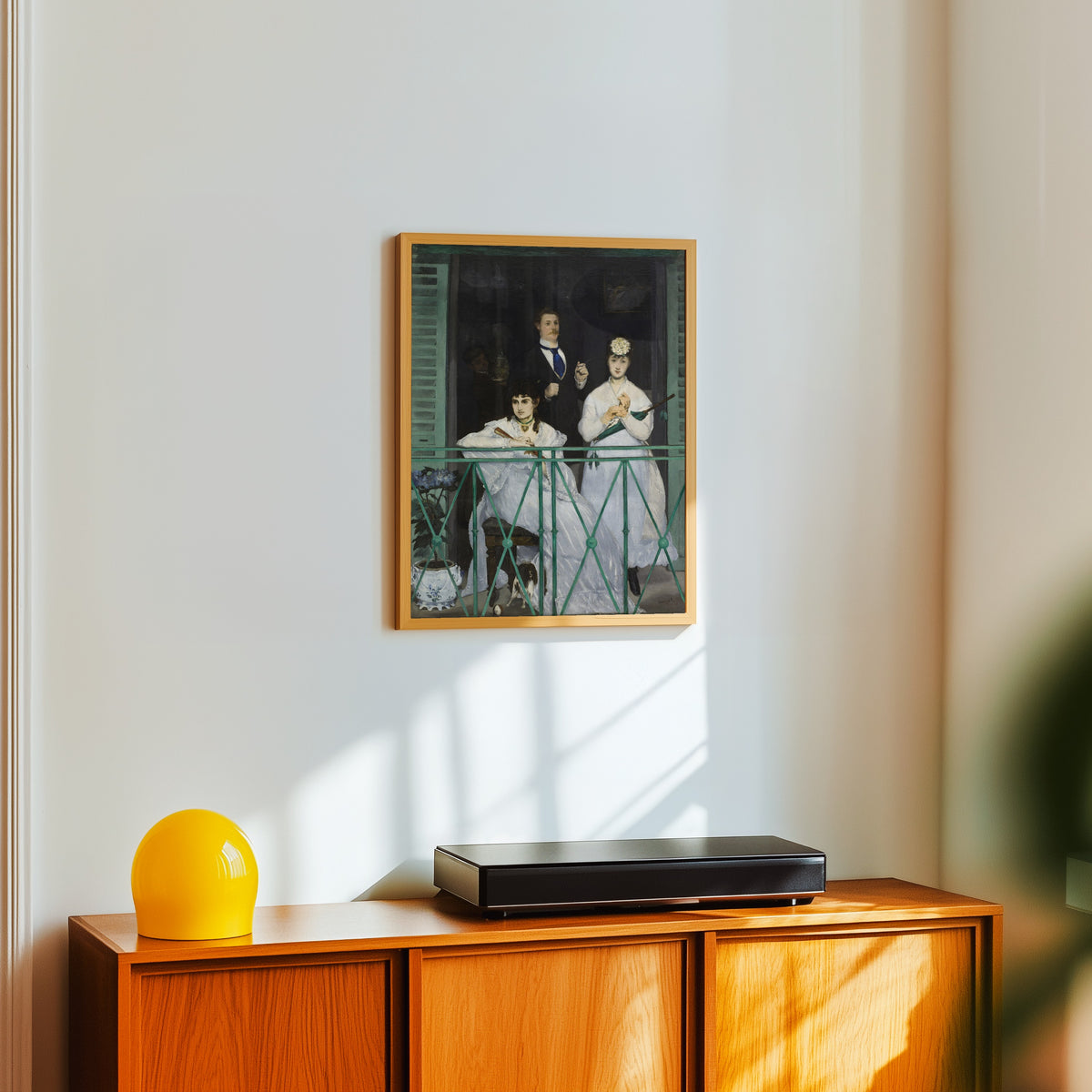 Framed art print of The Balcony by Édouard Manet, in a light wood frame on a white wall above an orange sideboard
