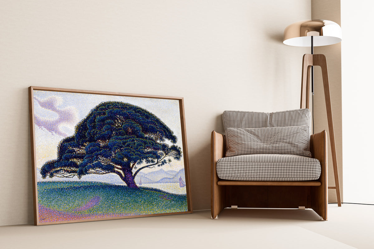 Framed art print of The Bonaventure Pine by Paul Signac, leaning against a wall beside an armchair and a floor lamp