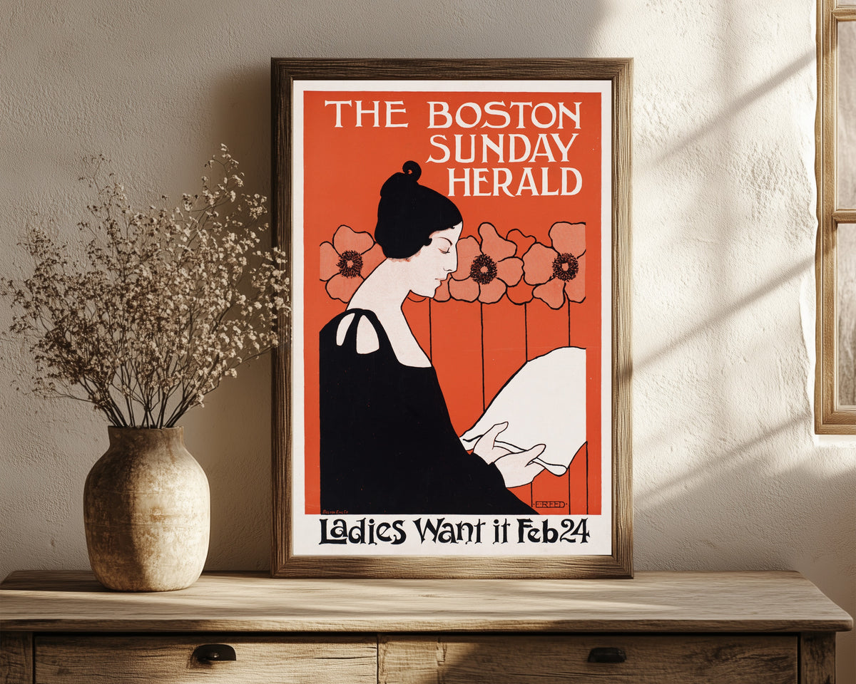 Framed art print of The Boston Sunday Herald, Ladies Want It, Feb 24 by Ethel Reed, in a dark wood frame leaning on a rustic console beside dried flowers