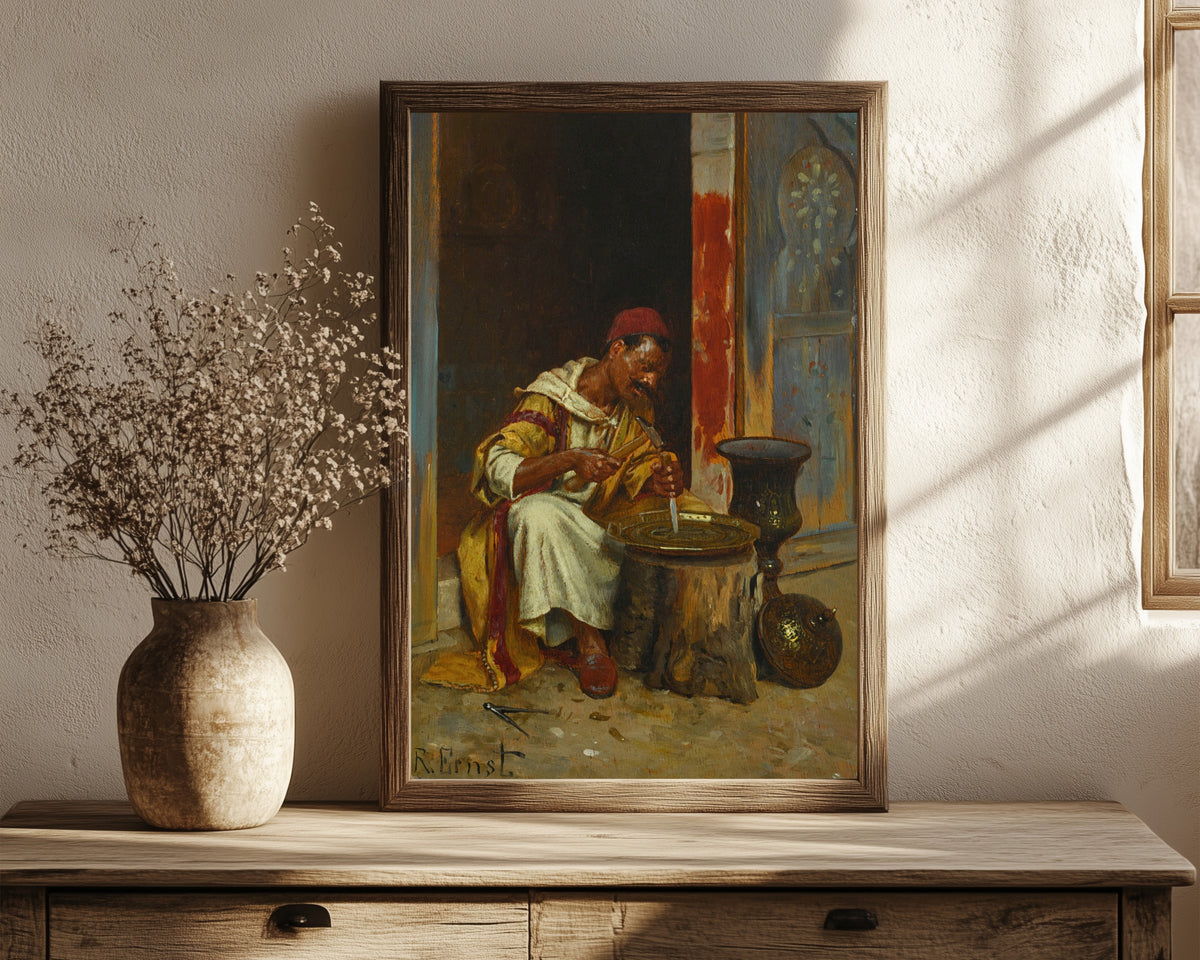 Framed art print of The Brass Worker by Rudolf Ernst, in a dark wood frame leaning on a rustic console beside dried flowers